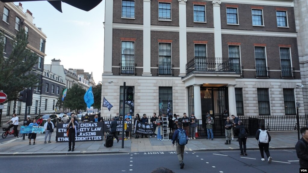 2026年10月1日,示威者在伦敦中国驻英国大使馆外集会,展示声援香港及维吾尔人的旗帜和标语。|来源:美国之音 / 李伯安