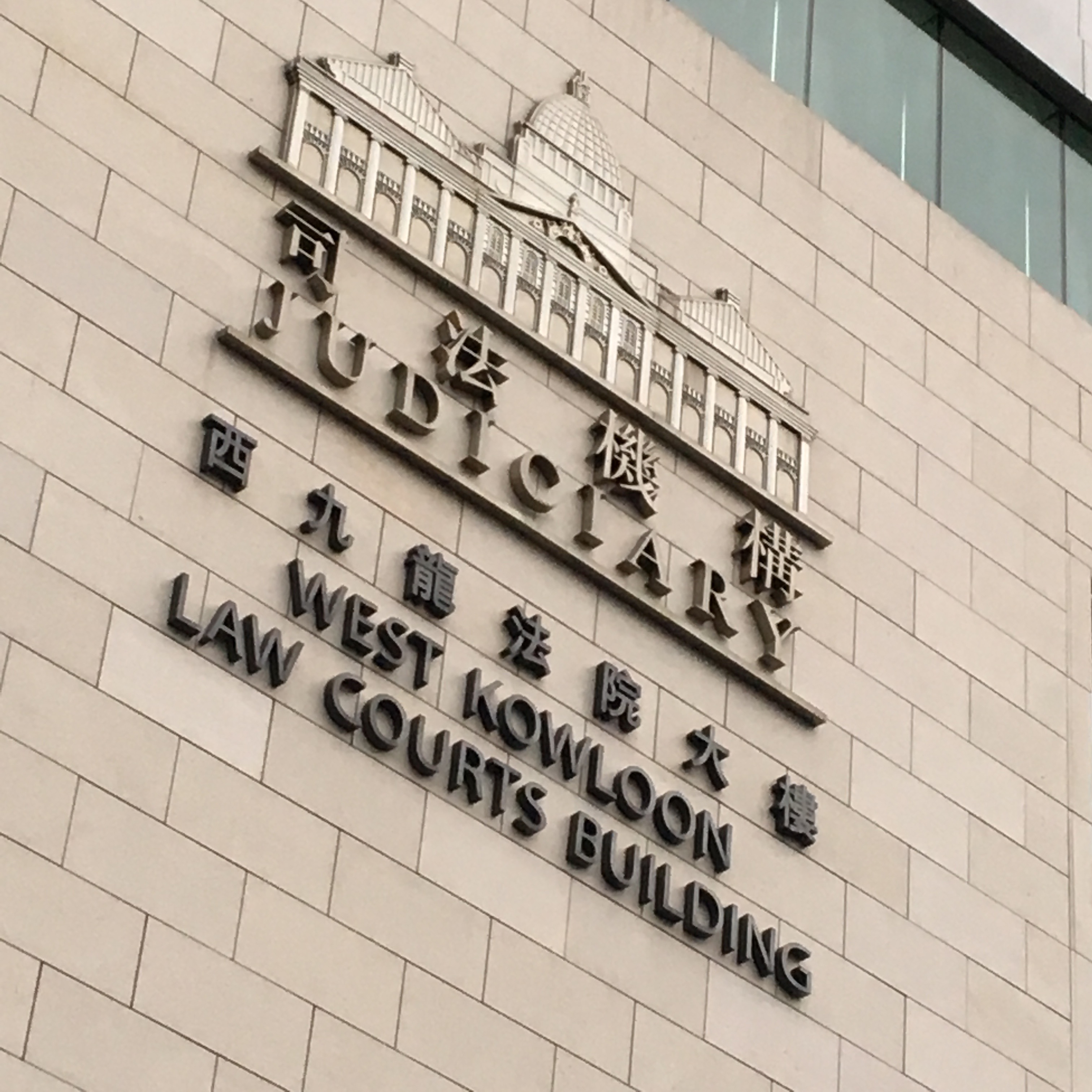 西九龙法院大楼标牌。52岁被告于2026年10月7日在该院提堂。资料照片，摄影：Scotted400｜来源：Wikimedia Commons / Scotted400