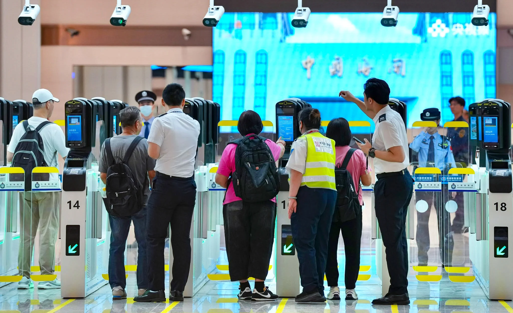 2026年10月12日新皇岗口岸启用首日,旅客与工作人员在合作查验自动闸机区域。不同于封面车辆排队照片|来源:南华早报/Karma Lo