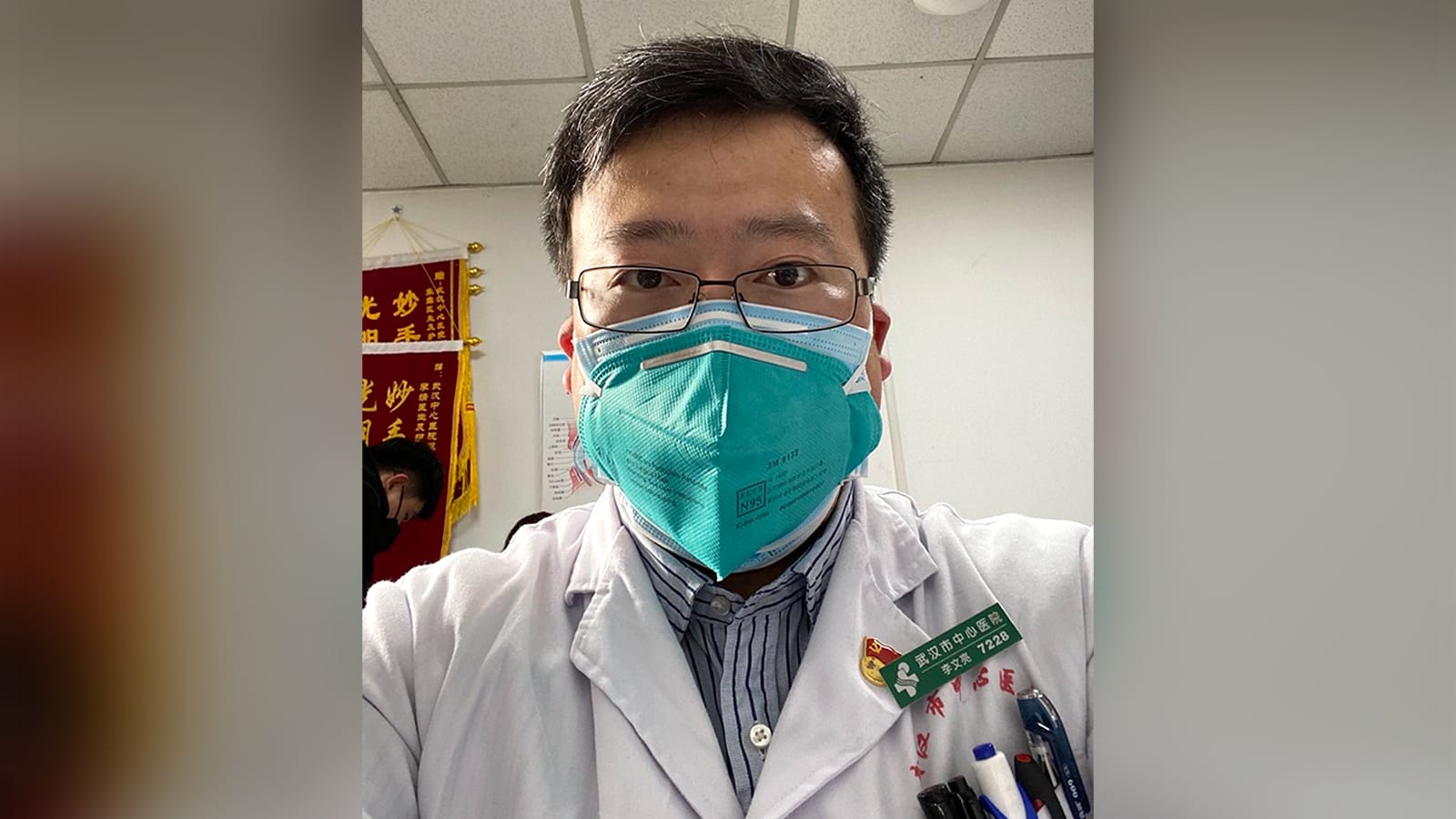 武汉市中心医院医生李文亮生前身穿白大褂及防护口罩的资料照片;不是2020年1月3日警方训诫现场|来源:CNN阿拉伯语版 / 原始图片版权保留